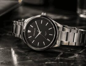 Relógio masculino Seculus de aço inoxidável sobre superfície de mármore escuro, luz natural lateral, fundo desfocado, ênfase nos detalhes do mostrador e pulseira