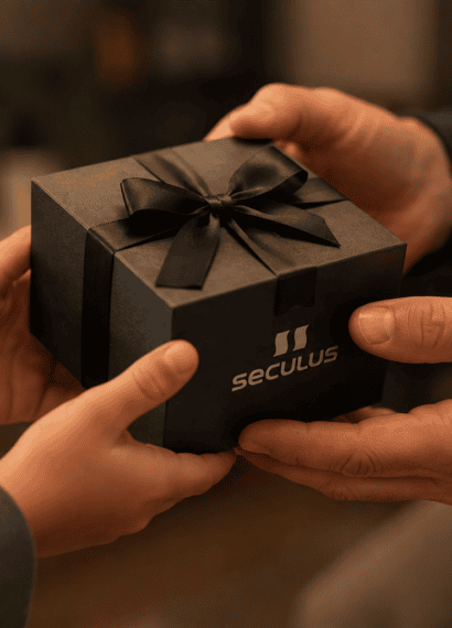 Mãos de um filho entregando uma caixa de presente Seculus ao pai, com foco no gesto de entrega. Ao fundo, ambiente desfocado com iluminação quente, transmitindo um clima familiar, acolhedor e afetuoso.