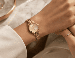 Pulso feminino usando relógio Seculus dourado de caixa pequena, combinado com anel solitário, em composição delicada e elegante.
