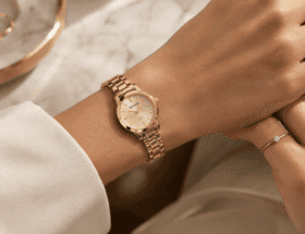 Pulso feminino usando relógio Seculus dourado de caixa pequena, combinado com anel solitário, em composição delicada e elegante.