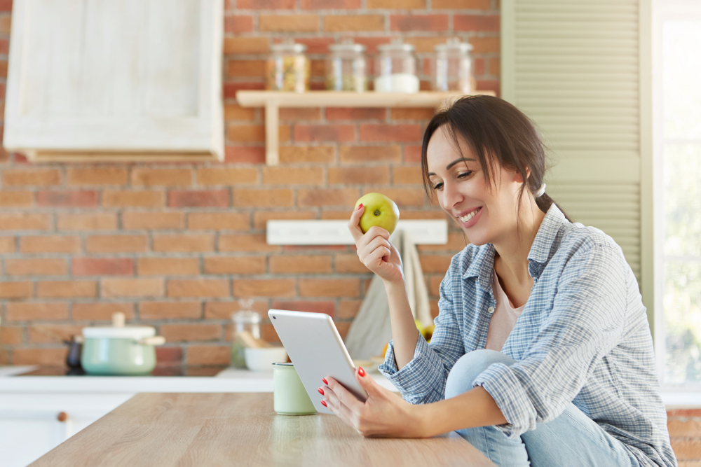 7 dicas para fortalecer a imunidade - Moça trabalhando com um tablet e comendo uma maçã