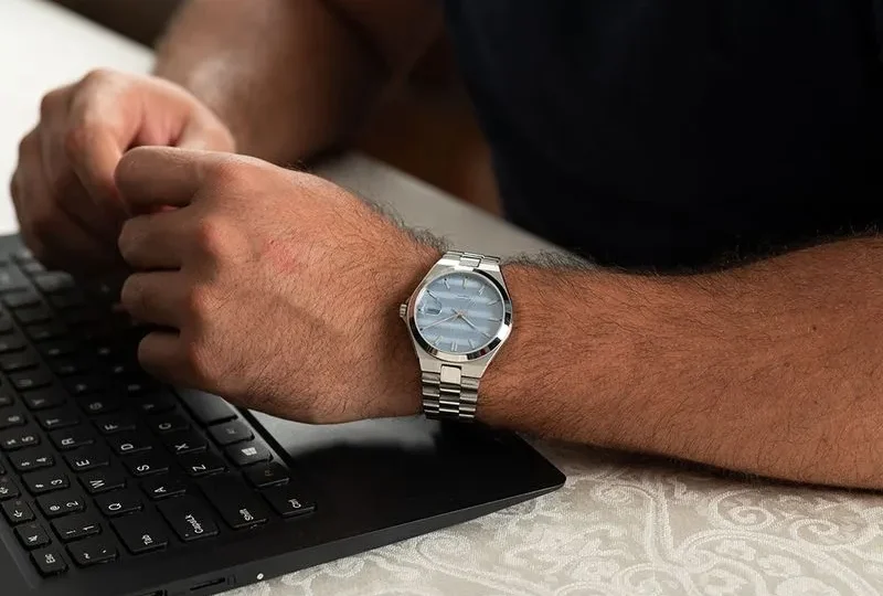 Homem utilizando relógio masculino Seculus Automático Fundo Transparente Visor Azul enquanto trabalha em um notebook, destacando o design elegante e versátil para o cotidiano.