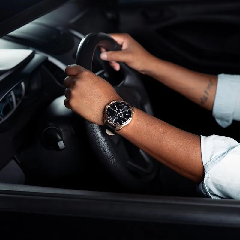  Relógio masculino Seculus cronógrafo com caixa rosé gold, mostrador preto com submostradores e pulseira de couro marrom, usado por motorista ao volante, transmitindo sofisticação e presença no dia a dia.