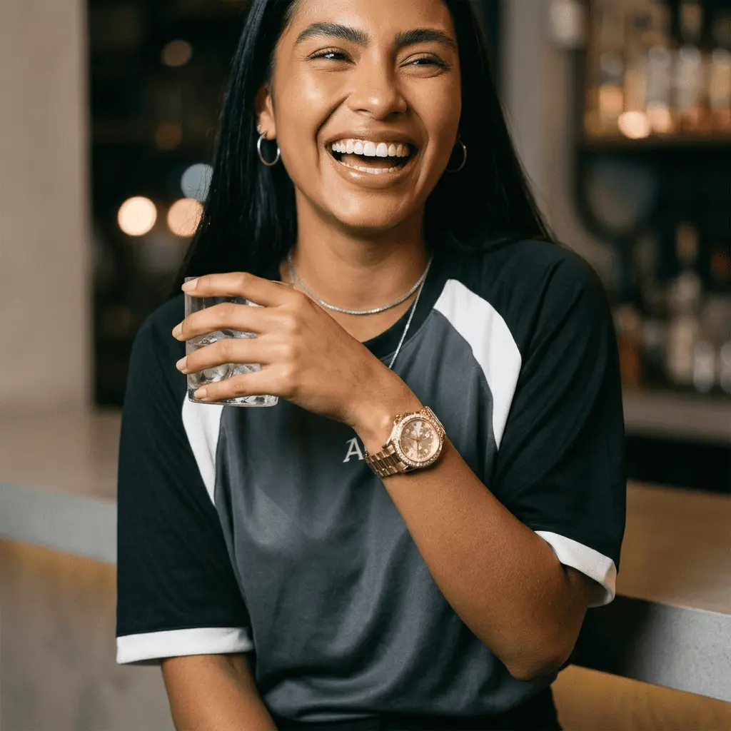 Mulher sorrindo em ambiente interno usando o Relógio Feminino Analógico Aço Bicolor com Cristais e Calendário no pulso, combinado com camiseta casual e acessórios delicados, em destaque sob luz ambiente quente
