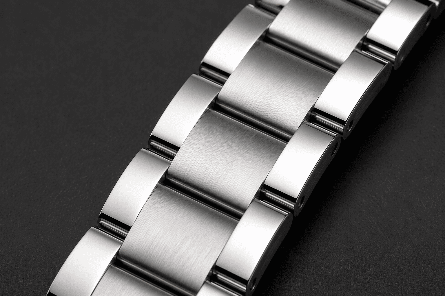 Close de pulseira estilo Oyster em aço, com três fileiras de elos largos e planos, acabamento escovado no centro e polido nas laterais.