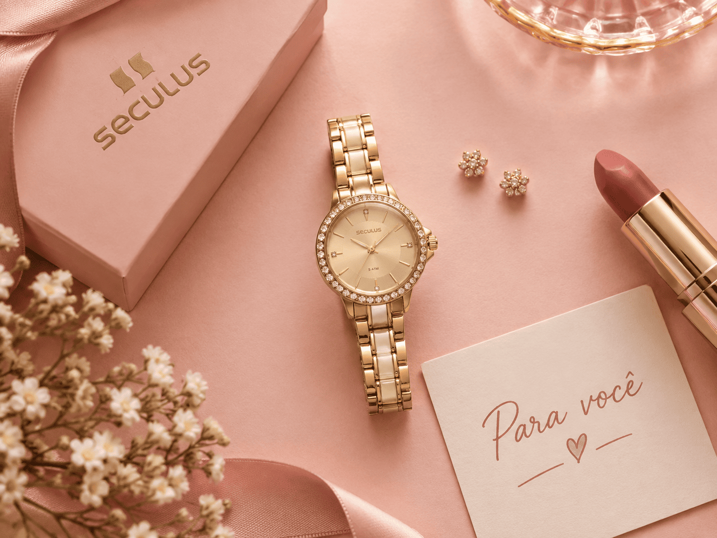 Flat lay de relógio feminino Seculus dourado ao centro, acompanhado de brincos delicados, batom e cartão escrito “Para você”, sobre fundo rosa claro.